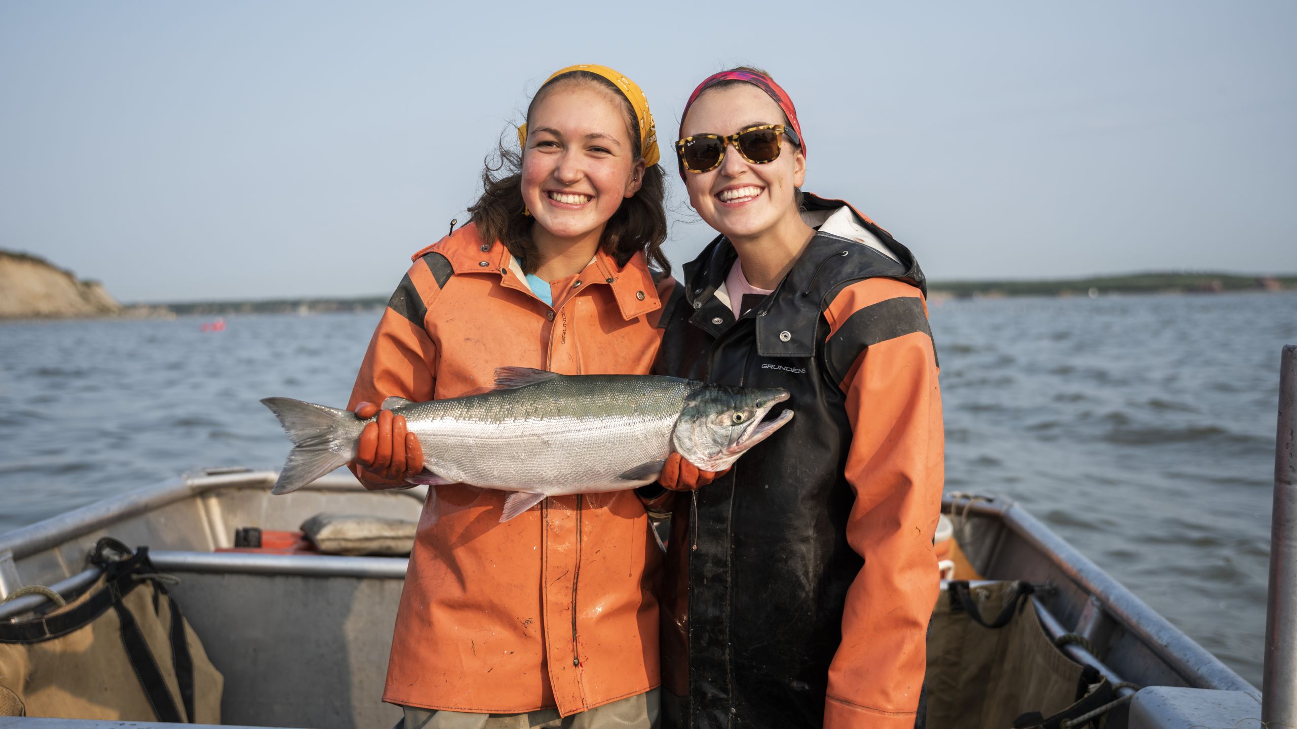 Two young fisher women holding a salmon